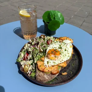 Toast Pepper met zoete aardappel, frisse salade en een gebakken ei op een terrastafel