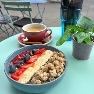 Yoghurtbowl met granola, verse aardbeien, bosbessen en banaan in een blauwe kom